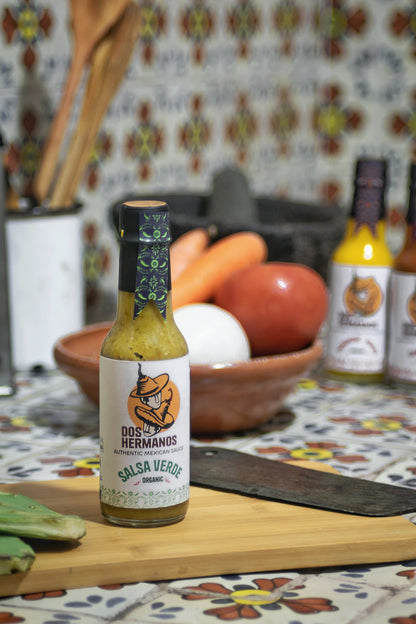 Dos Hermanos Salsa Verde bottle.

Salsa verde being scooped with a tortilla chip.

Ingredients used to make salsa verde.