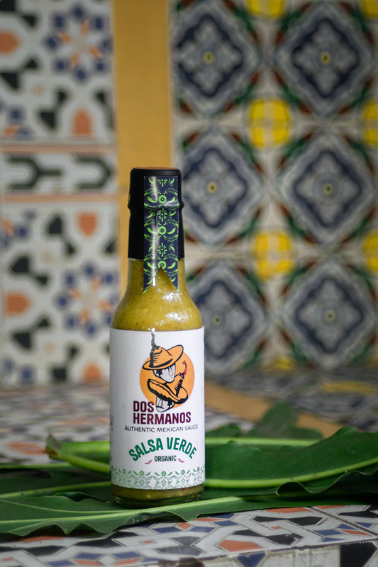 Dos Hermanos Salsa Verde bottle.

Salsa verde being scooped with a tortilla chip.

Ingredients used to make salsa verde.
